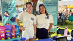 Two PupGrade team members smiling at the Walk for Whiskers booth with products displayed in front of branded banners.