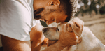 Close-up of a man affectionately cuddling his senior dog outdoors, highlighting emotional bond and comfort for aging dogs.