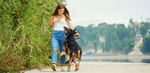 Happy woman walking her German Shepherd dog along a scenic trail, emphasizing outdoor activity and mood improvement